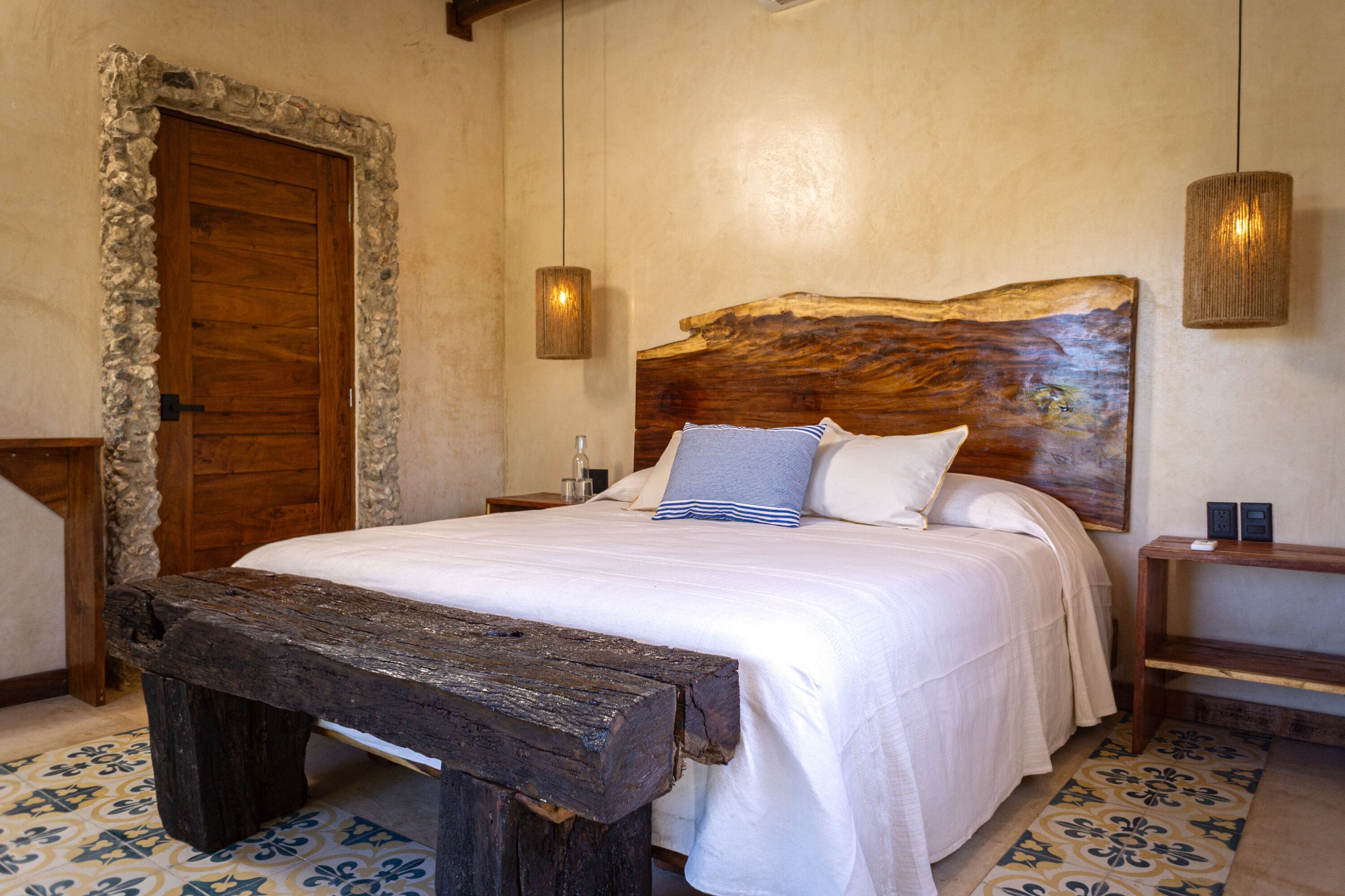 A bedroom with a large bed, wooden headboard, bedside tables, and a bench.