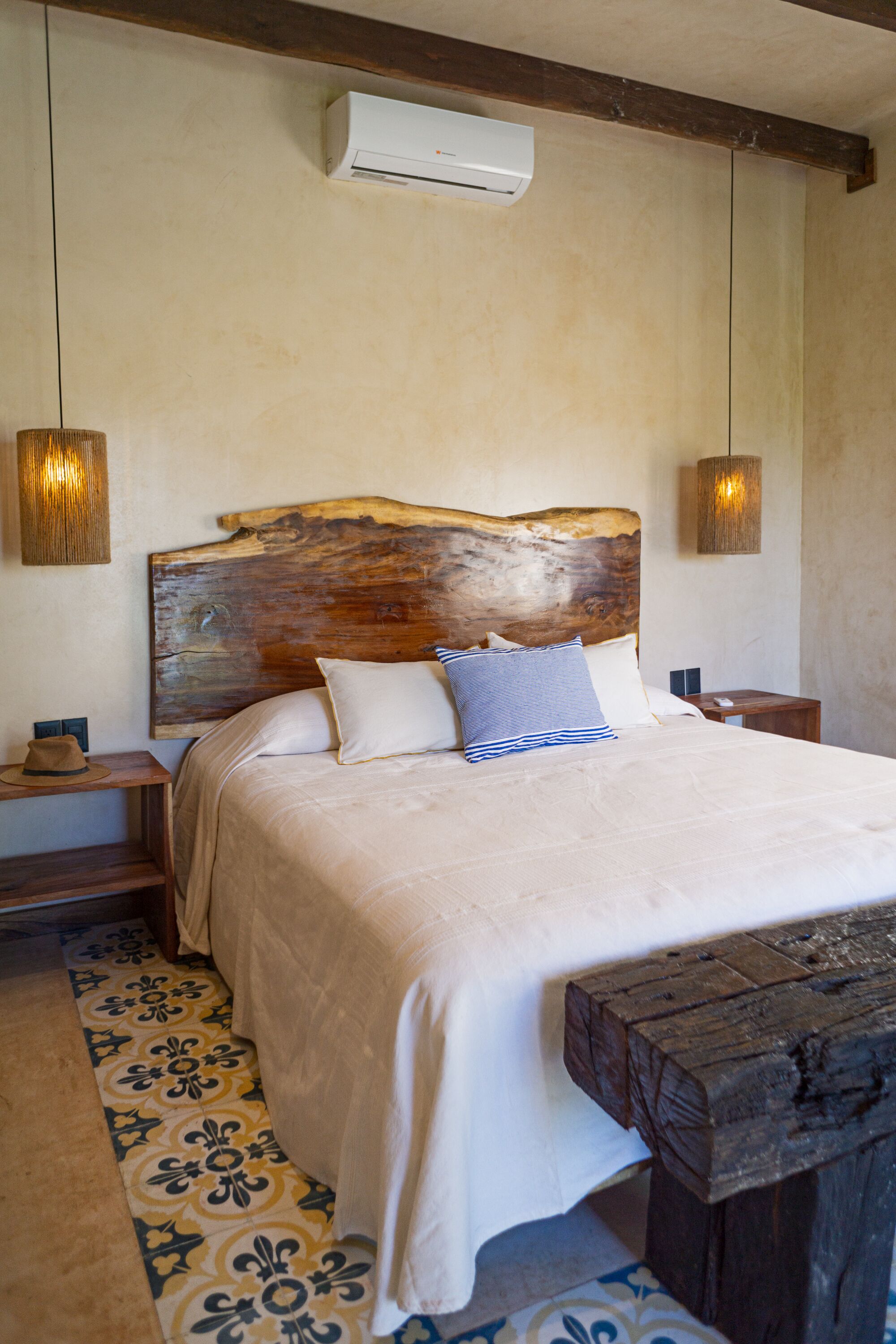 Une chambre avec un grand lit, une tête de lit en bois, des tables de chevet et un tapis à motifs.