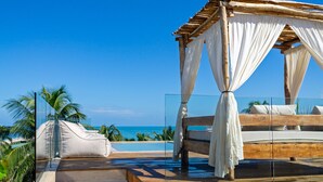 A wooden staircase leading to a bed with a canopy, overlooking a pool and beach. - Mero Mero Hotel (El Cuyo)