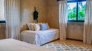 A bedroom with a large bed, a smaller bed, and a window with curtains.