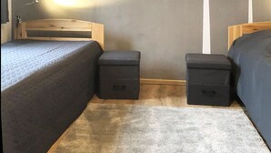 A bedroom with two beds, a wooden headboard, a small bedside table, a nightstand, and a rug. - Apartment Kornkammer near Lake Plau (Halenbeck-Rohlsdorf)