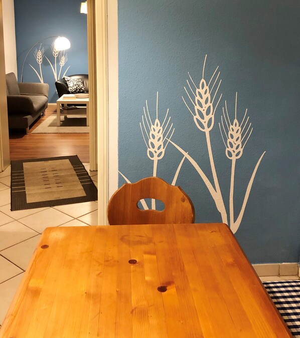 Enjoy meals in this cozy dining area with a table and chair, surrounded by a decorative wheat pattern on the wall.