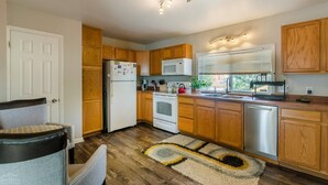 Une cuisine compacte avec des meubles de rangement en bois, un réfrigérateur, un four à micro-ondes, une cuisinière et un évier.