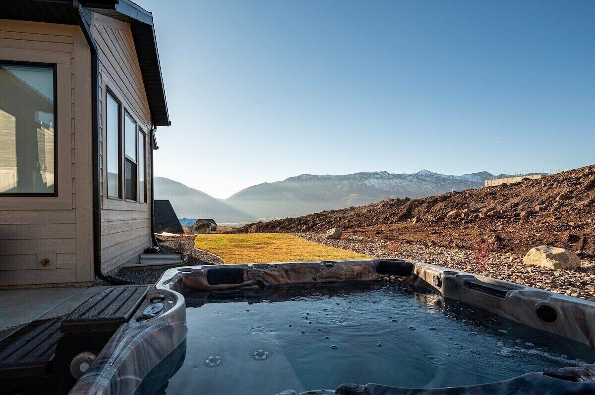 Een hottub met uitzicht op bergen en een houten gebouw.