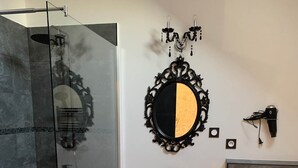 Un baño con cabina de ducha de vidrio, un tocador negro con espejo y un inodoro blanco.