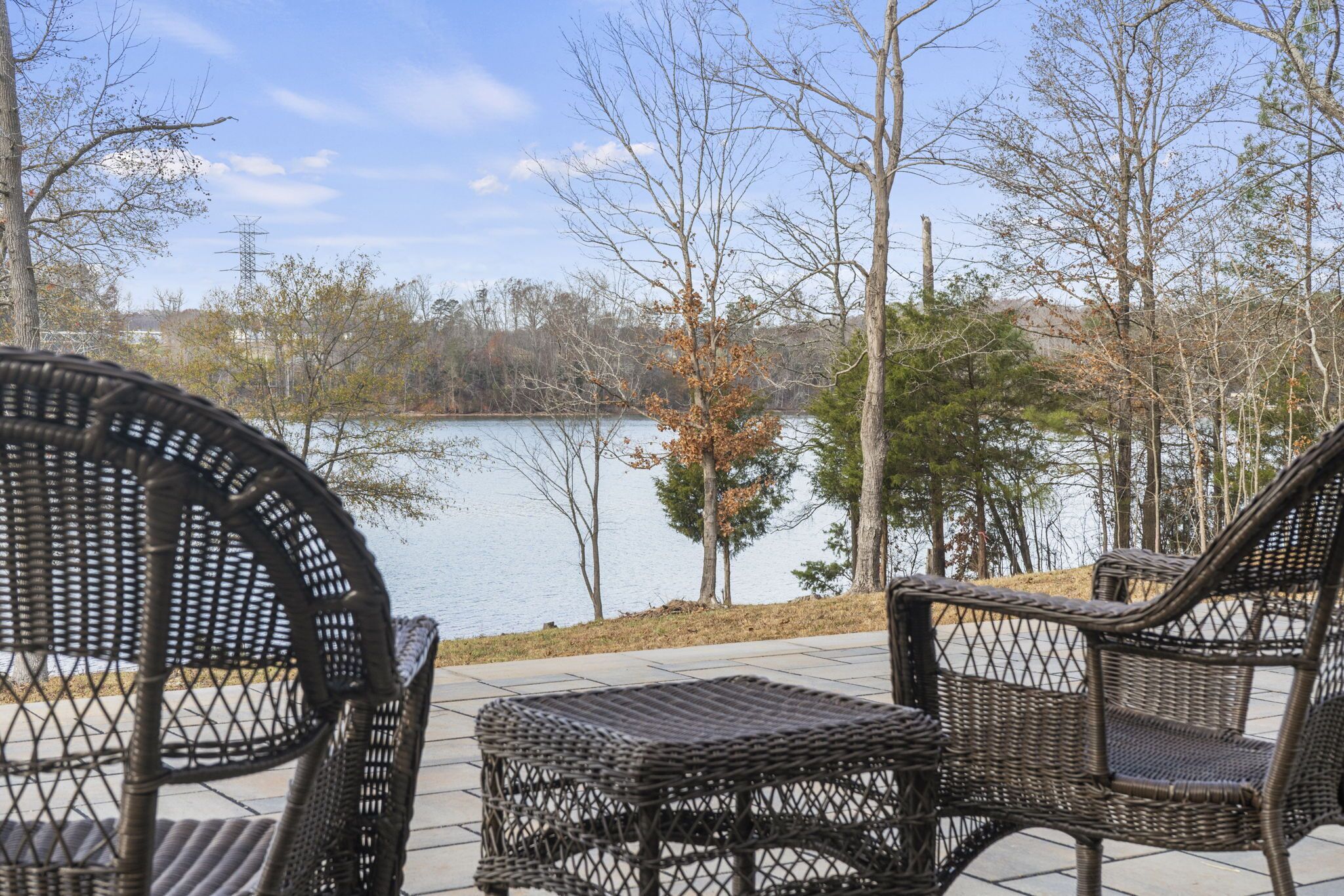 A patio area with wicker furniture and a view of a lake.