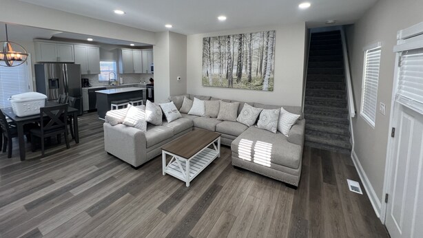 A modern living room with a sectional sofa, a coffee table, and a dining area with a table and chairs. - PERFECT - LARGE CUSTOM HOME - Completely Renovated, Beautiful Fenced in Yard!!!! (Indianapolis)