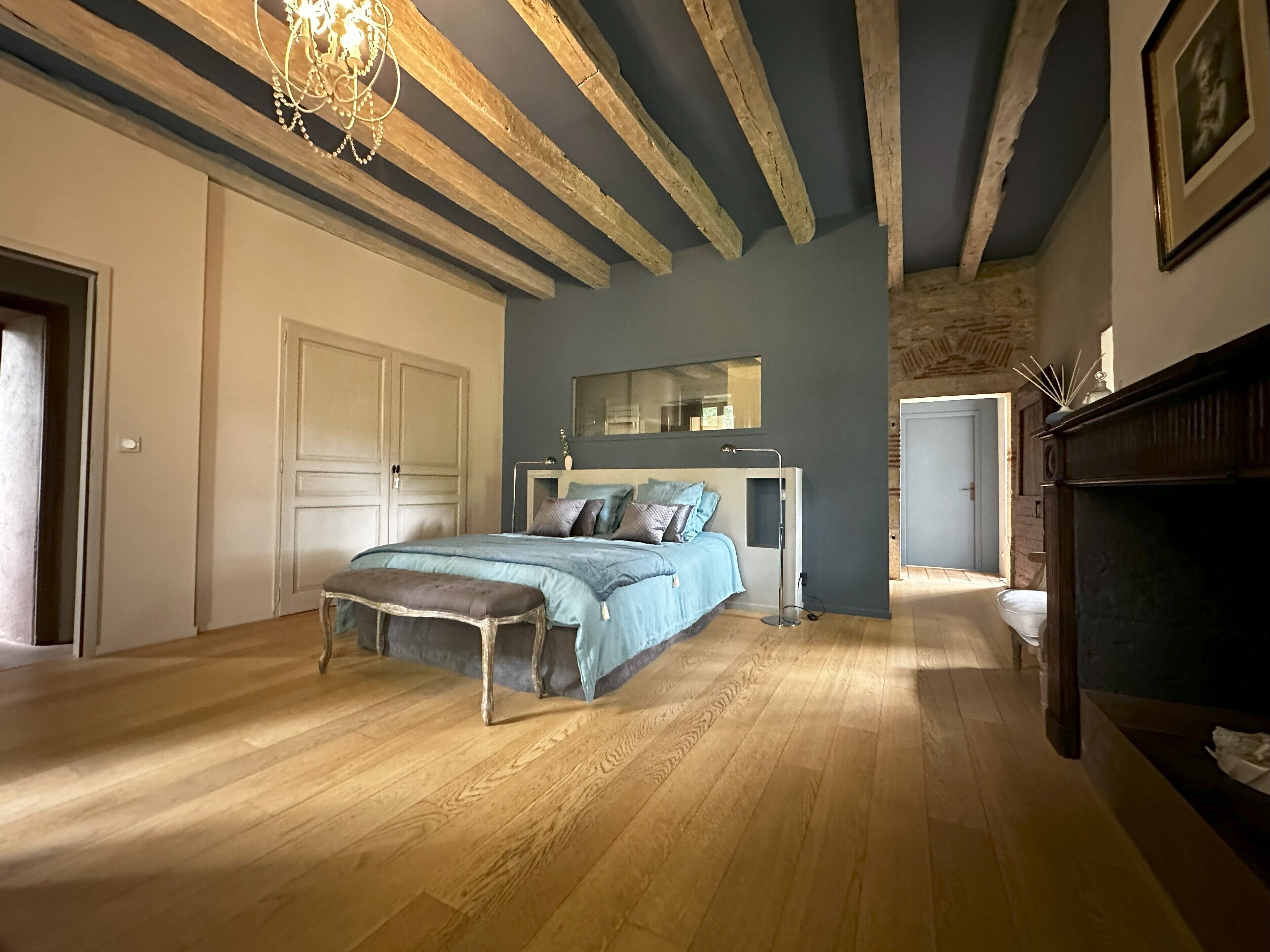 A bedroom with a bed, bench, wardrobe, and a mirror.