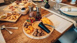 Una taula de dinar de fusta amb diversos aliments, com ara fruita, nous i formatges, acompanyats de condiments i un menú.