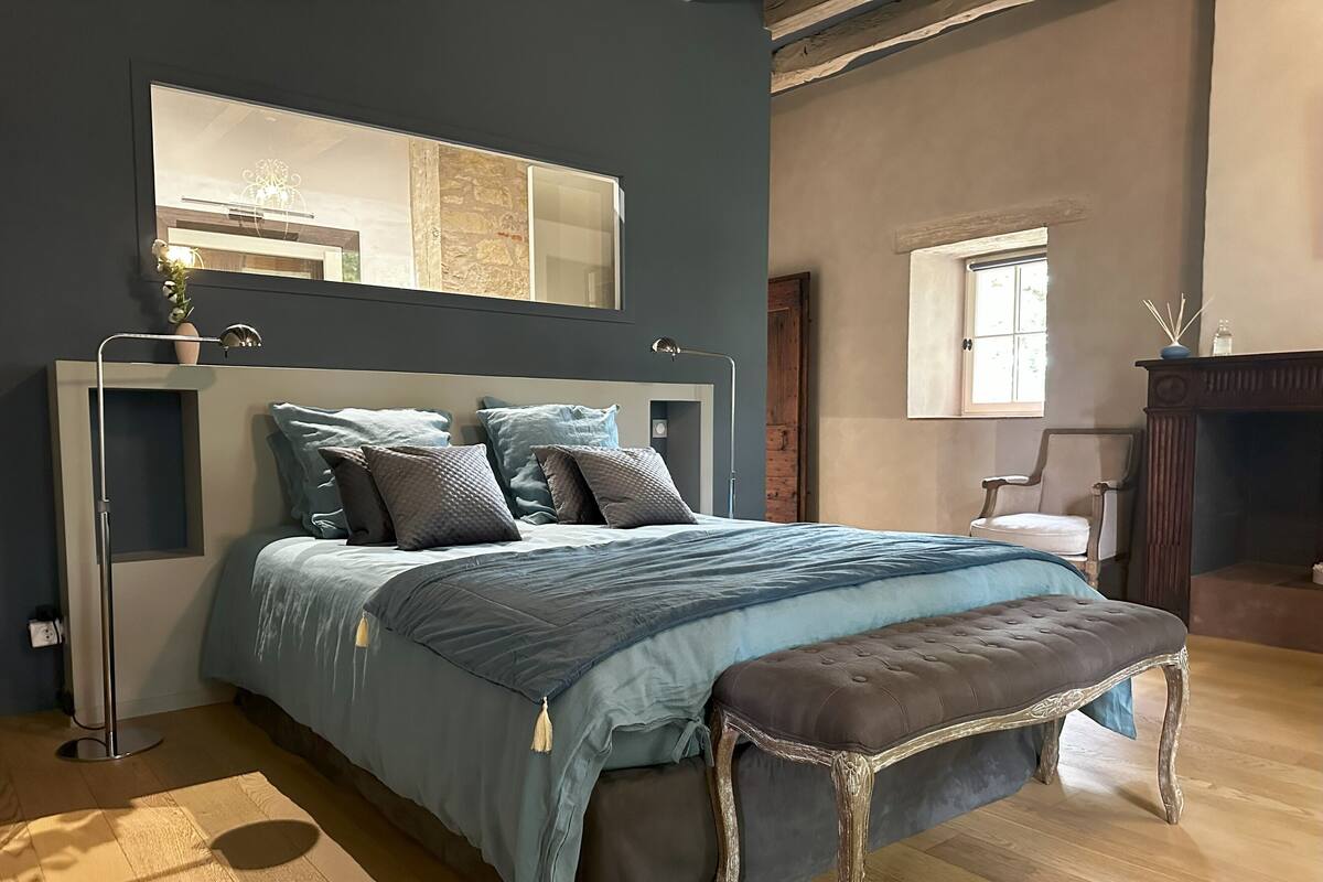 Ein Schlafzimmer mit einem großen Bett, einem Nachttisch, einem Spiegel und einem Fenster.