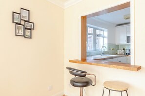 A modern kitchen with a large window, a wooden countertop, and two bar stools.