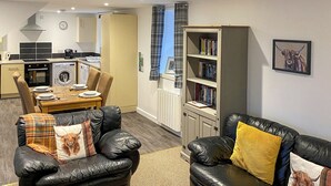 Una sala moderna con comedor, cocina y una estantería.