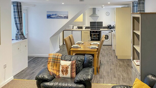 Eine moderne Wohnung mit Essbereich, Küche und Wohnzimmer mit Sofa und Hocker.