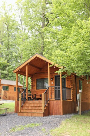 A wooden cabin with a porch, a staircase, and a picnic table.