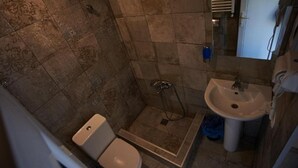 Une petite salle de bain avec des toilettes, une douche et un lavabo.