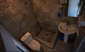 Pieni kylpyhuone, jossa on wc, suihku ja pesuallas.