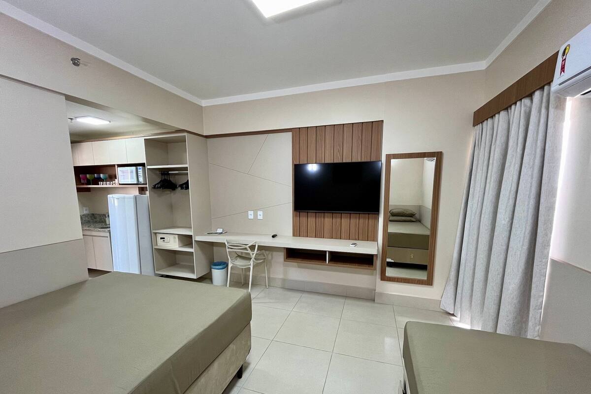 A hotel room with a bed, a desk, a chair, a TV, and a wardrobe.