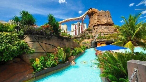A water park with a water slide, a pool, and lush greenery. - Spazzio diRoma Com Parque Acqua Splash (Caldas Novas)