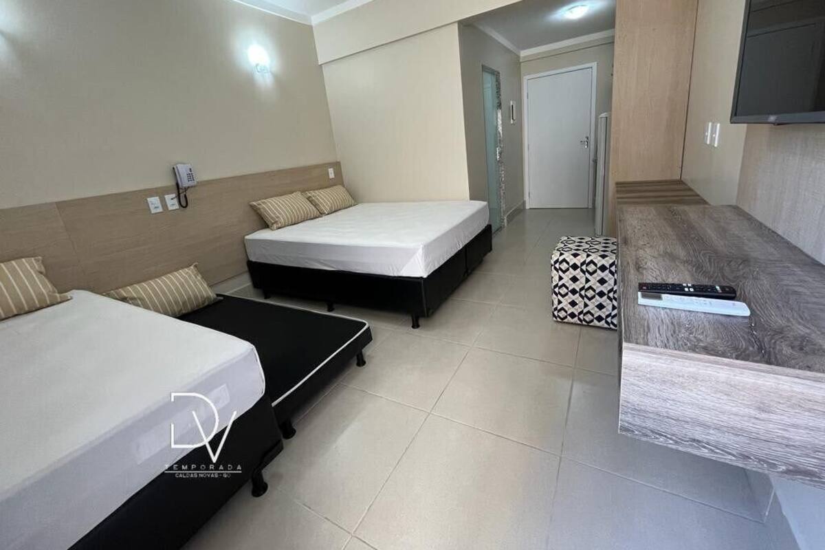 A hotel room with two beds, a desk, a phone, and a TV.