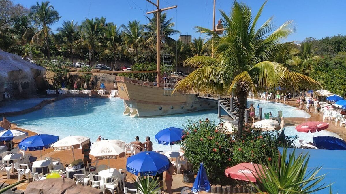 Ein Swimmingpool mit einem schiffartigen Schwimmpflege, umgeben von Palmen und Liegestühlen.