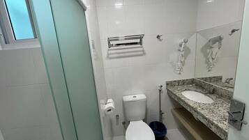 A bathroom with a toilet, a sink, a mirror, and a trash bin.