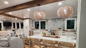 Una cocina moderna con una isla central, sillas de madera e iluminación colgante.