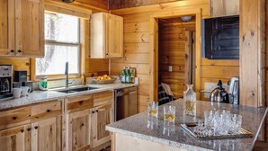 Eine Holzhüttenküche mit Granitarbeitsplatte, Holzschränken, einem Spülbecken und einer Kaffeemaschine.
