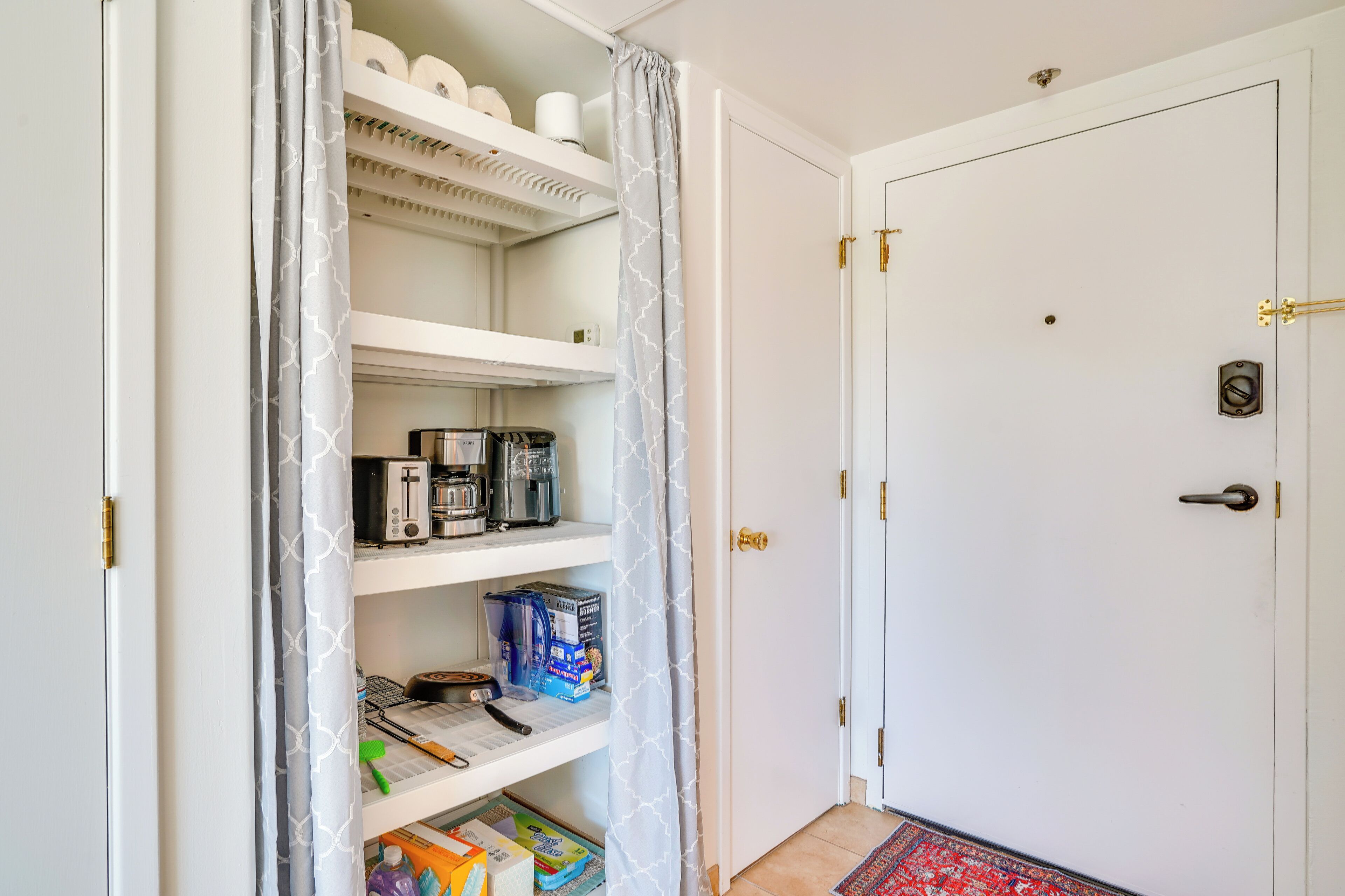 A kitchen with white cabinets, a coffee machine, and various kitchen items on shelves.
