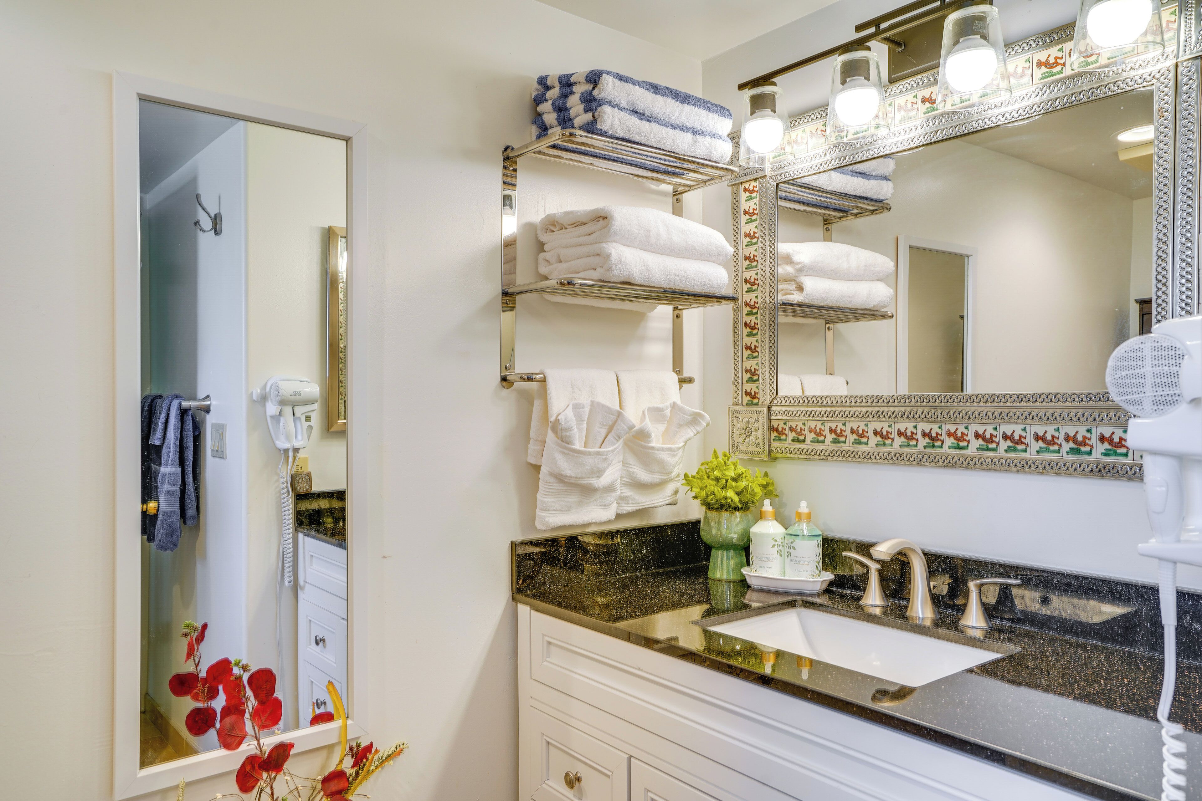 A bathroom with a large mirror, a sink, and a towel rack with neatly folded towels.