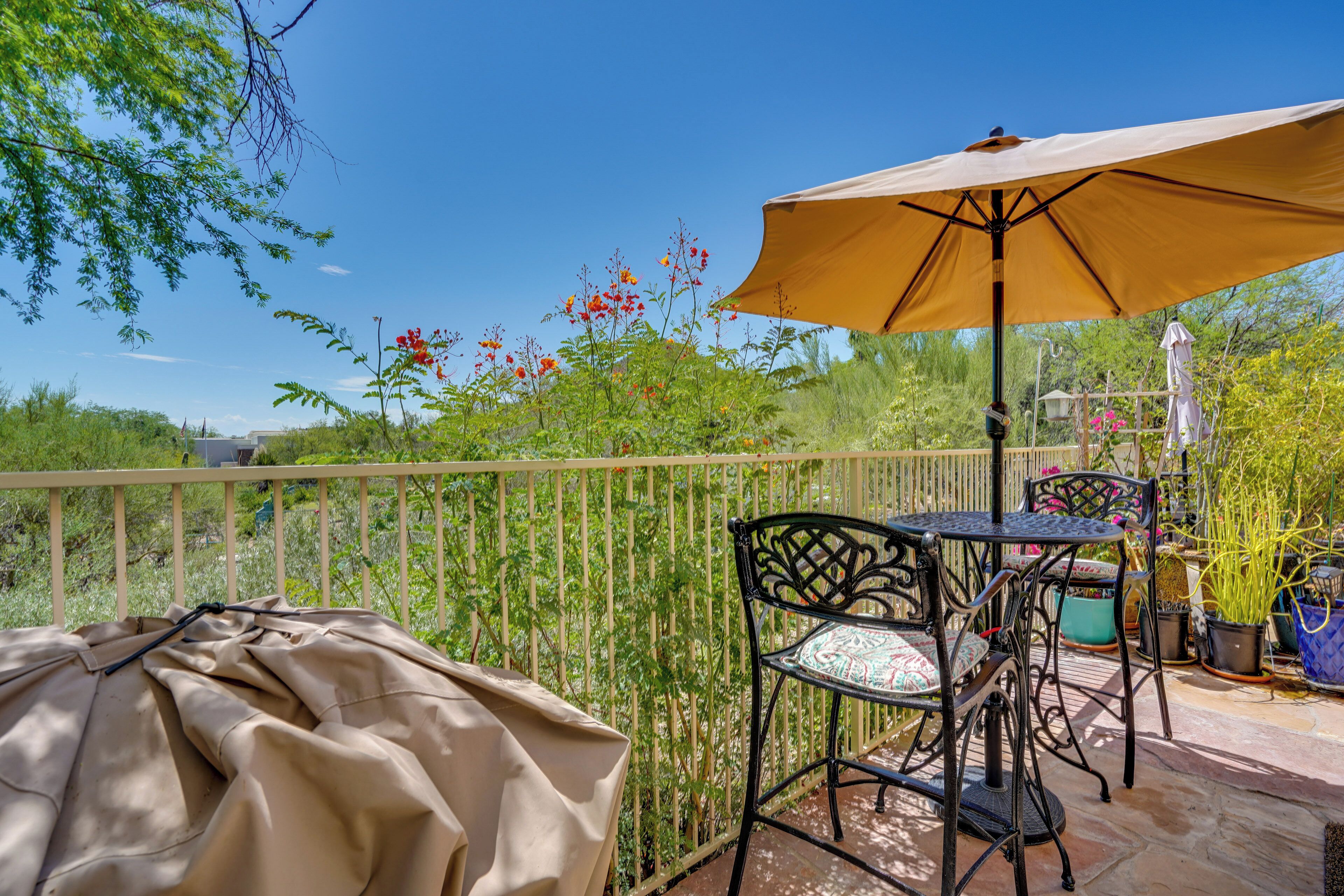 A patio with a table and chairs, a covered table, and an umbrella.