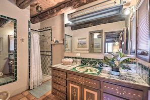 Une salle de bain avec une douche, un lavabo agrémenté d’un pare-éclaboussures décoratif en carrelage et un miroir au-dessus du lavabo.