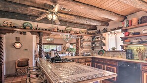Een landelijke keuken met een groot eiland, houten balken en diverse keukengerei en decoraties.