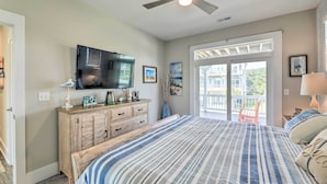 A bedroom with a bed, a dresser, a TV, and a balcony with a chair. - Charming Surf City Home w/ Elevator: Walk to Beach (Holly Ridge)
