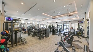 A spacious gym with various exercise equipment, large windows, and a modern ceiling design. - Luxe Naples Bay Resort Condo: Near Fifth Ave! (Naples)