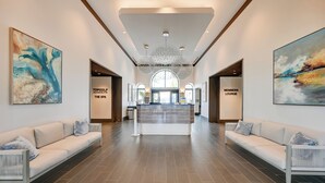 A spacious lobby with a reception desk, two sofas, and artwork on the walls. - Luxe Naples Bay Resort Condo: Near Fifth Ave! (Naples)