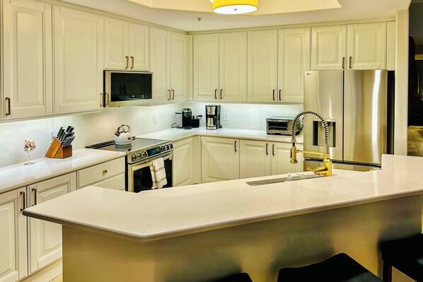A modern kitchen with white cabinets, stainless steel appliances, and a central island. - Luxe Naples Bay Resort Condo: Near Fifth Ave! (Naples)