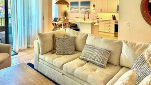 A modern living room with a beige sofa, a coffee table, and a dining area with a laptop. - Luxe Naples Bay Resort Condo: Near Fifth Ave! (Naples)