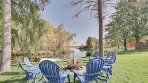 Uma área externa à beira do lago com cadeiras Adirondack e uma lareira.