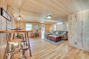 A spacious wooden interior with a bar area, seating, and a large window providing natural light.