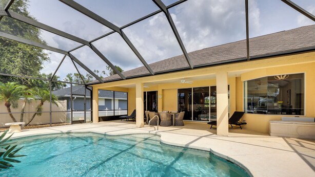 An indoor swimming pool with clear water, surrounded by a covered patio area with chairs and tables. - Florida Vacation Rental w/ Private Pool & Lanai (North Port)