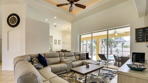 A spacious living room with a sectional sofa, a coffee table, and a view of the outdoors through large windows. - Florida Vacation Rental w/ Private Pool & Lanai (North Port)