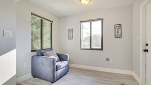 Una habitación con un sofá gris, dos ventanas y una lámpara.