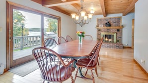 A dining room with a wooden table and chairs, a chandelier, and a brick fireplace. - Milton Hidden Gem w/ Pool, Hot Tub & Fireplace! (Milton)