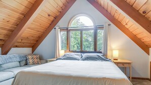 A bedroom with a large bed, a nightstand with a lamp, a window with curtains, and a wooden ceiling. - Milton Hidden Gem w/ Pool, Hot Tub & Fireplace! (Milton)