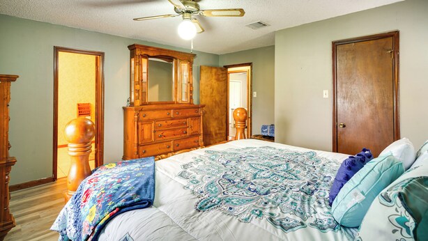 Une chambre à coucher avec un lit, une commode en bois et un ventilateur de plafond.