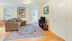 A living room with a sofa, a television, a rug, and a door. - Charming Chester Apartment: Steps to Main Street! (Chester)