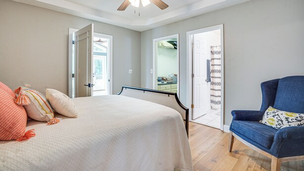 A bedroom with a bed, a chair, a ceiling fan, and a door leading to another room. - Waterfront Gilbertsville Retreat on Kentucky Lake! (Gilbertsville)
