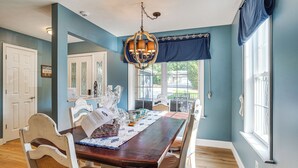 A dining room with a wooden table, white chairs, and a chandelier. - Waterfront Gilbertsville Retreat on Kentucky Lake! (Gilbertsville)