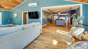 A spacious living area with a high ceiling, wooden flooring, and a blue accent wall. - Waterfront Gilbertsville Retreat on Kentucky Lake! (Gilbertsville)
