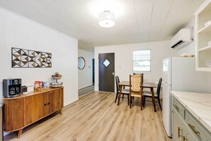 Cozinha compacta com área de refeições, piso de madeira e luminária moderna.